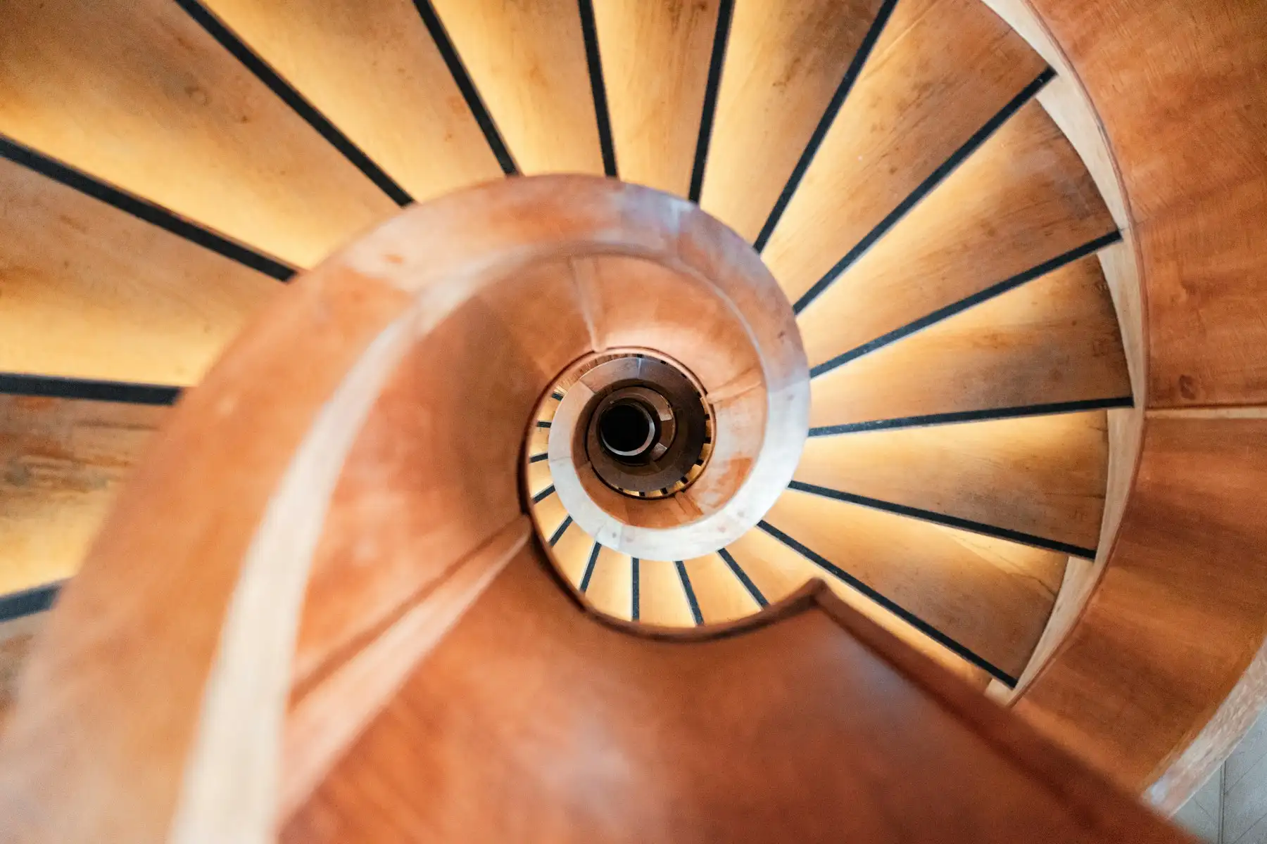 Holzwendeltreppe von oben, gebogener Handlauf und radial angeordnete Stufen