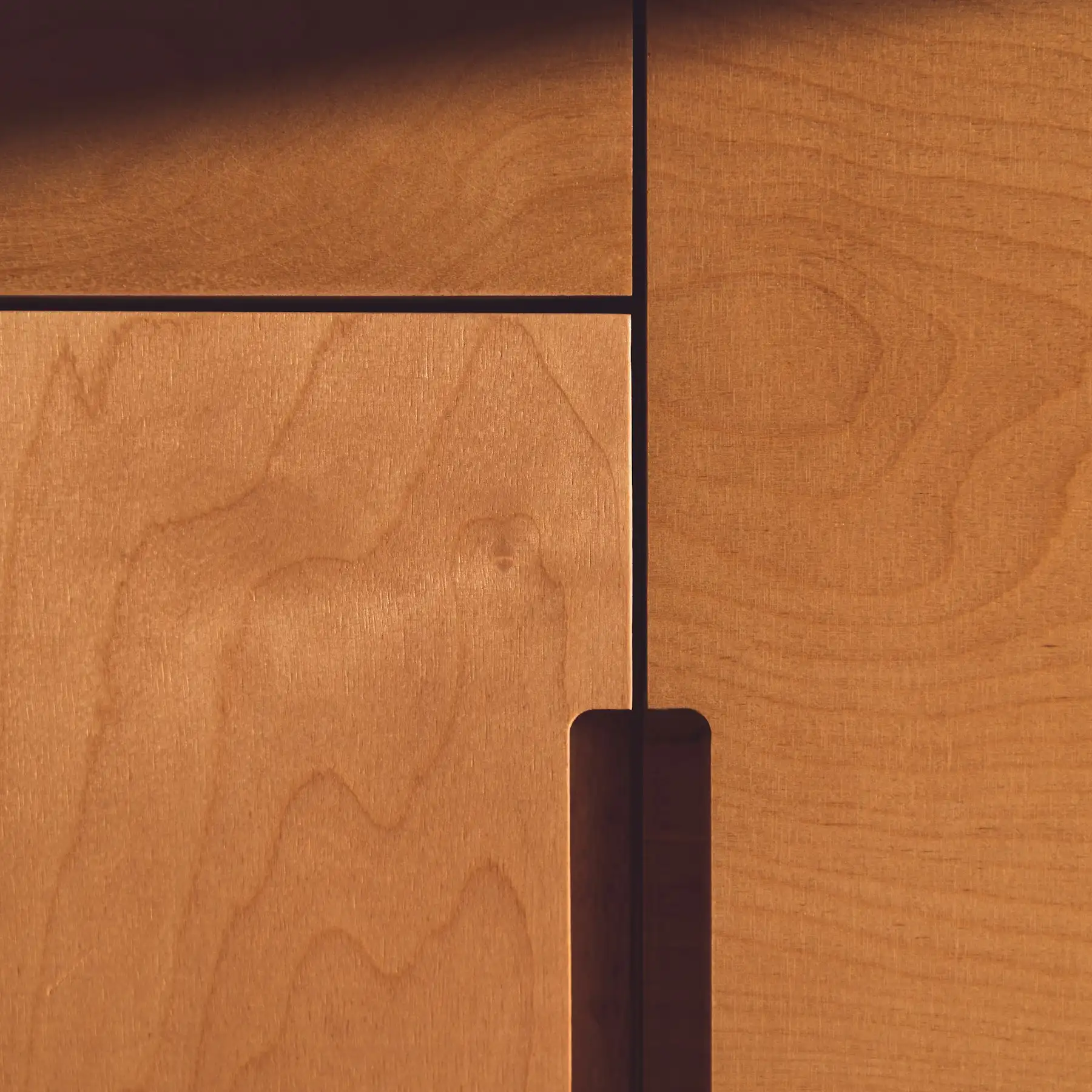 Detail von Fronten aus Obstbaumholz mit eingelassener Griffleiste aus dunklem Holz